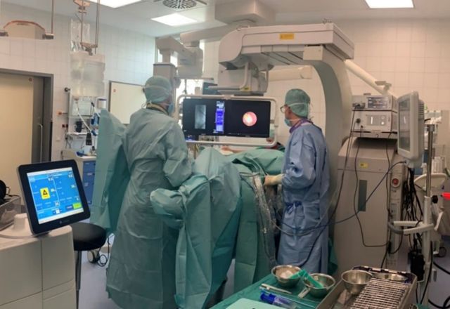 Abb. 2: ECIRS mit Operateur für URS zwischen den Beinen und Operateur für PNL an der linken Flanke. Beachte den separaten Monitor rechts im Bild für den URS-Operateur.