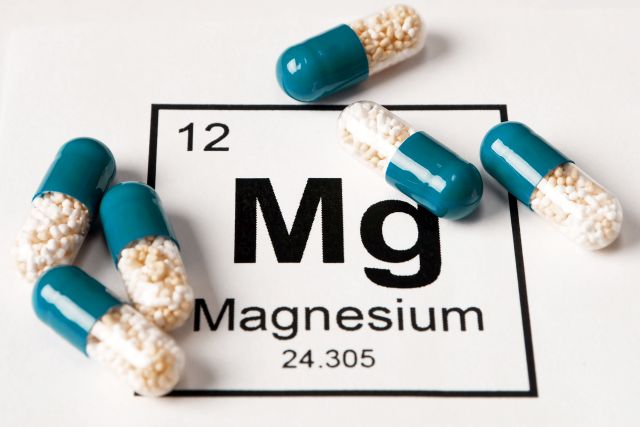 Pillen mit dem Mineral Mg (Magnesium) auf weißem Hintergrund mit einer Inschrift aus der Chemietabelle