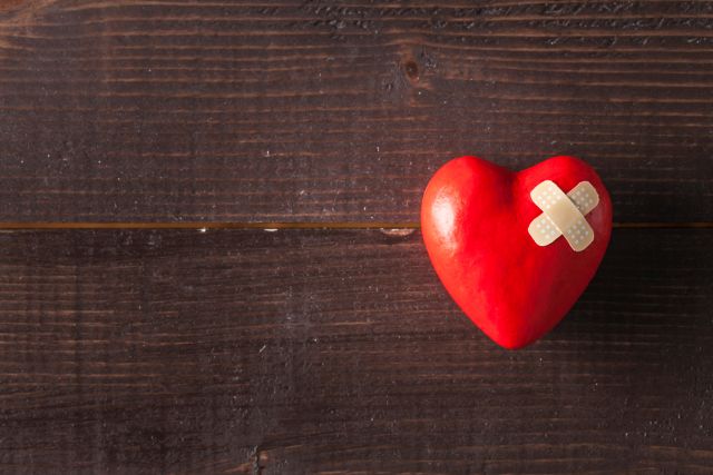 Rotes Herz auf braunem Holz mit Pflaster