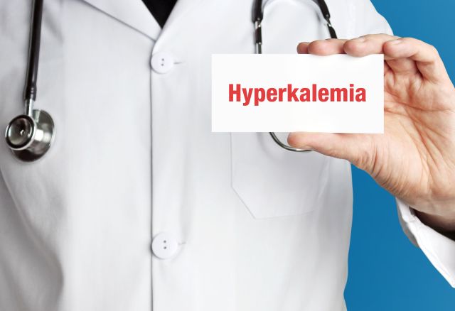 Hyperkaliämie. Arzt im Kittel hält Visitenkarte hoch. Der Begriff Hyperkaliämie steht im Zeichen. Symbol für Krankheit, Gesundheit, Medizin