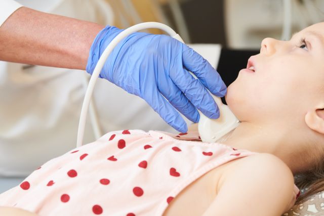 Ultraschalluntersuchung. Untersuchung der Schilddrüse einer kleinen Patientin in der Klinik. Frühzeitige Diagnose.
