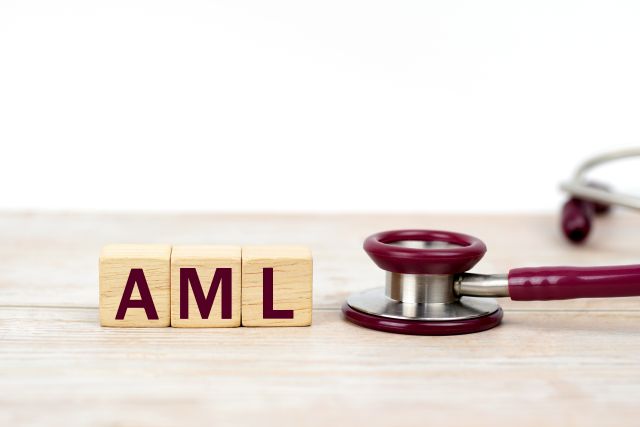 Wort AML (akute myeloische Leukämie) auf Holzklötzen und Stethoskop auf weißem Hintergrund. Leukämiebehandlung, Klinik- und Medizingeschäfte.Klinik- und Medizingeschäfte