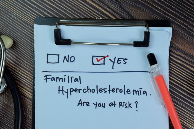 Familiäre Hypercholesterinämie, sind Sie gefährdet? Ja, schreiben Sie auf einen Papierzettel, der auf einem Holztisch isoliert ist.