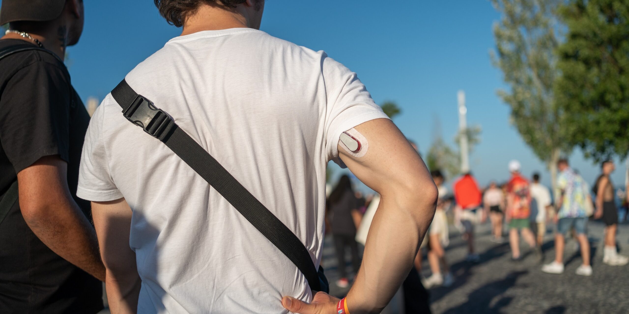 Symbolbild, Tourist mit einem CGM-Sensor am Oberarm an einem sonnigen Tag