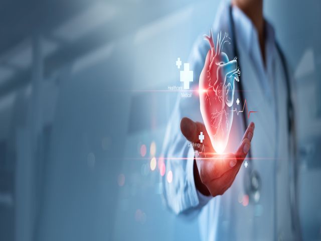Arzt hält ein digitales 3D-Bild eines Herzens mit medizinischen Symbolen im Hintergrund