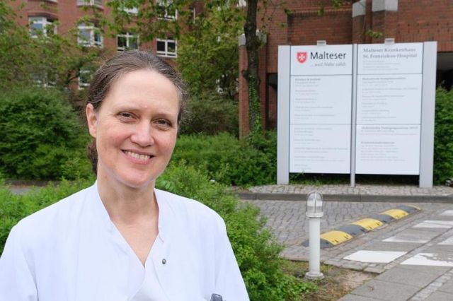 Das Foto zeigt Prof. Dr. med. Angela Krackhardt vor dem Malteser Krankenhaus St. Franziskus-Hospital.