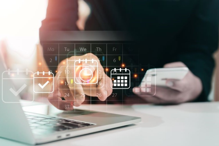 Hand berührt digitalen Kalender auf Laptop-Bildschirm. Mehrere Kalendericons schweben darüber.