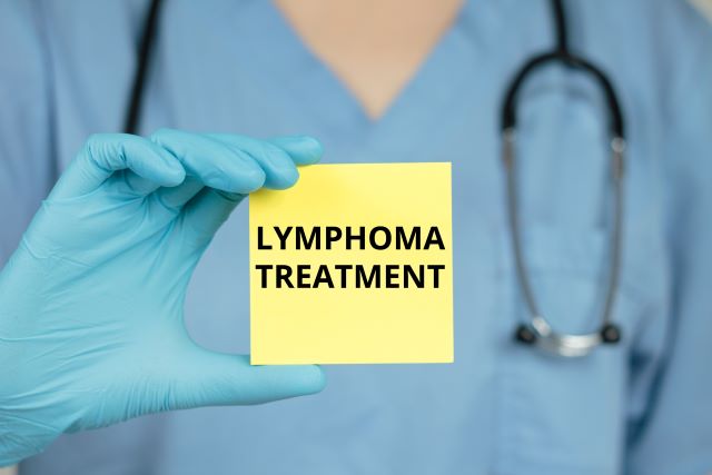Arzt in blauer Uniform hält ein gelbes Post-it mit der Aufschrift "Lymphoma Treatment" in der Hand.