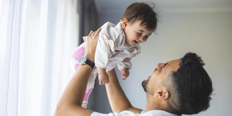 Vater hält fröhliches kleines Kind hoch