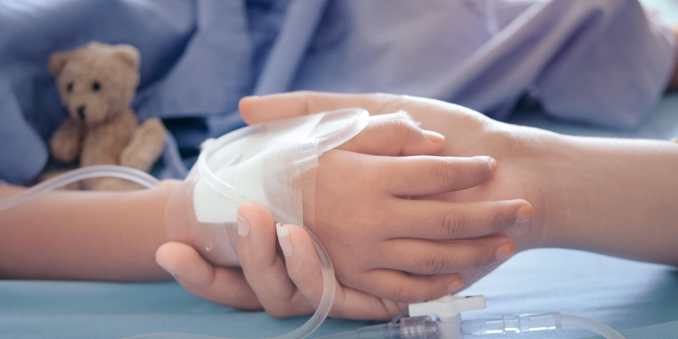 Mutter hält Kinderhand mit Venenkatheter
