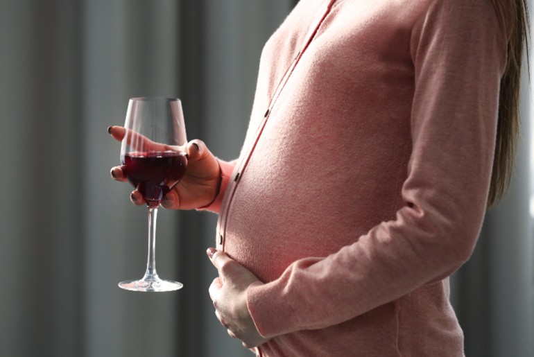 Schwangere Frau mit Rotweinglas