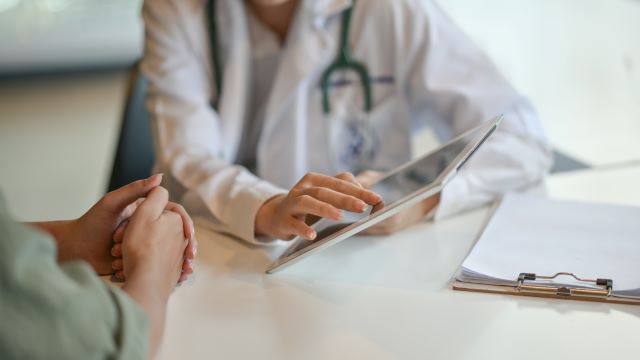 Arzt erklärt Patientin medizinische Informationen auf einem Tablet