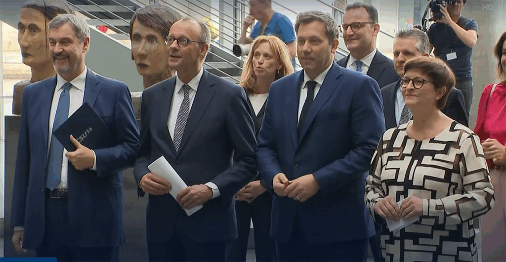 Gruppe von Personen in Anzügen bei einer Veranstaltung in einem modernen Gebäude.