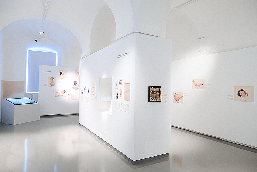 Innenansicht einer modernen Ausstellung mit Kunstwerken und interaktiven Displays in einer Galerie.