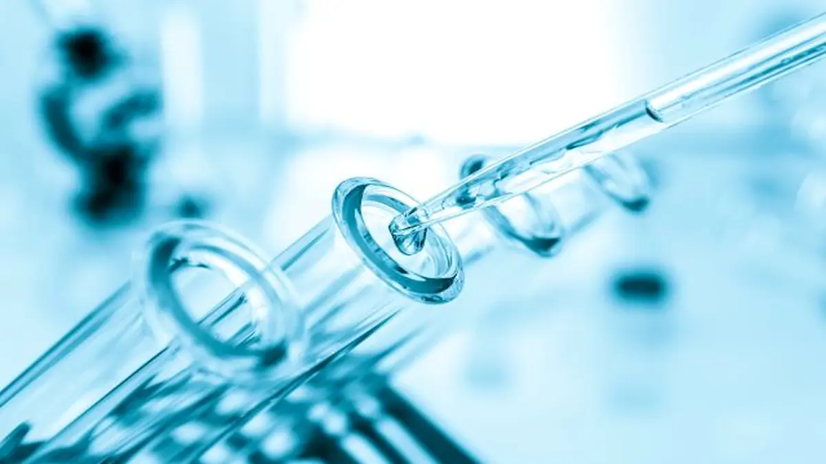 Eine Pipette tropft Flüssigkeit in ein Reagenzglas in einem chemischen Labor.