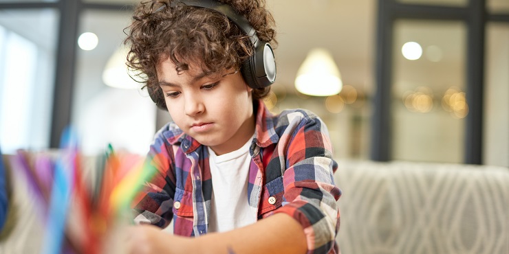 Kind hat Kopfhörer auf und zeichnet