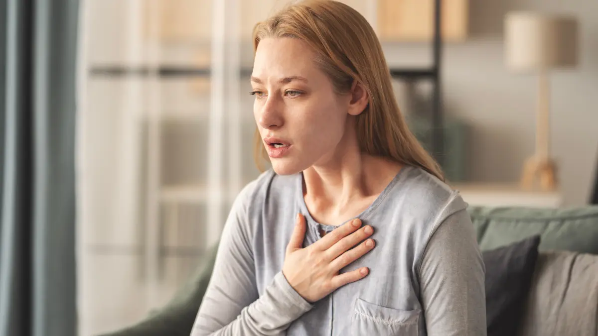 Frau di e sich sie Brust hält und unter Atemnot leidet