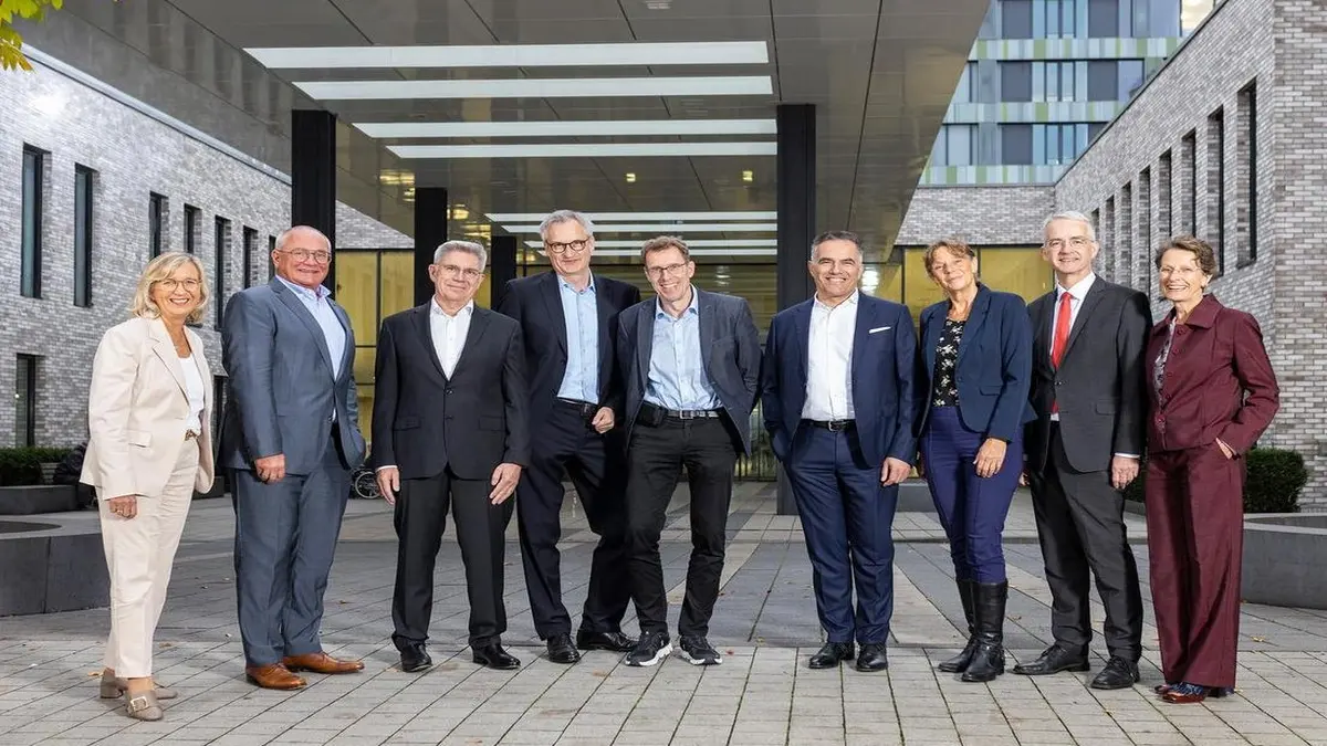 Gruppe von Personen in Businesskleidung vor dem Eingang eines modernen Klinikgebäudes.