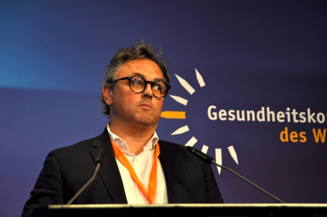 Sprecher auf dem Gesundheitskongress des Westens 2025 vor einer Bühne mit Logo im Hintergrund.