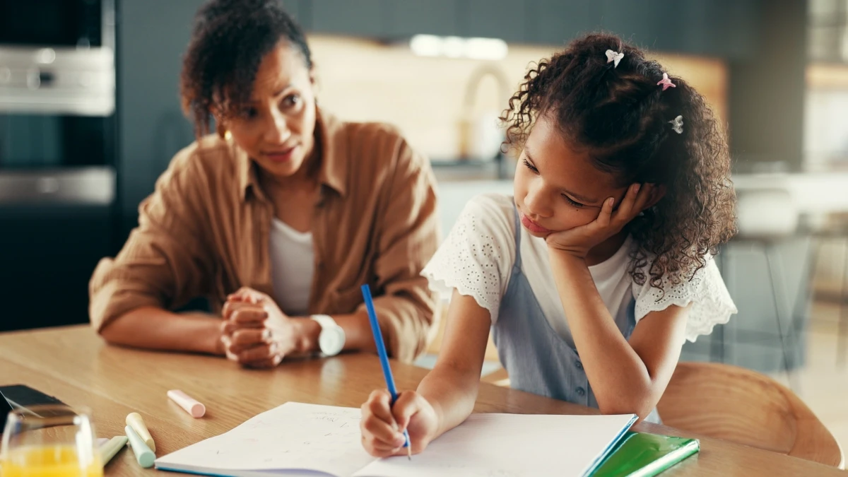 Mutter unterstützt Tochter mit ADHS beim Lernen Zuhause, beide sitzen am Schreibtisch