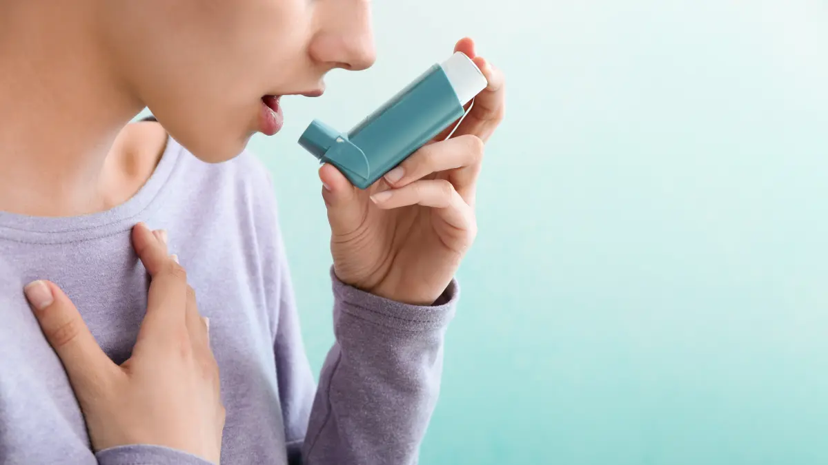 Person verwendet Asthma-Inhalator zur Behandlung von Atemwegssymptomen