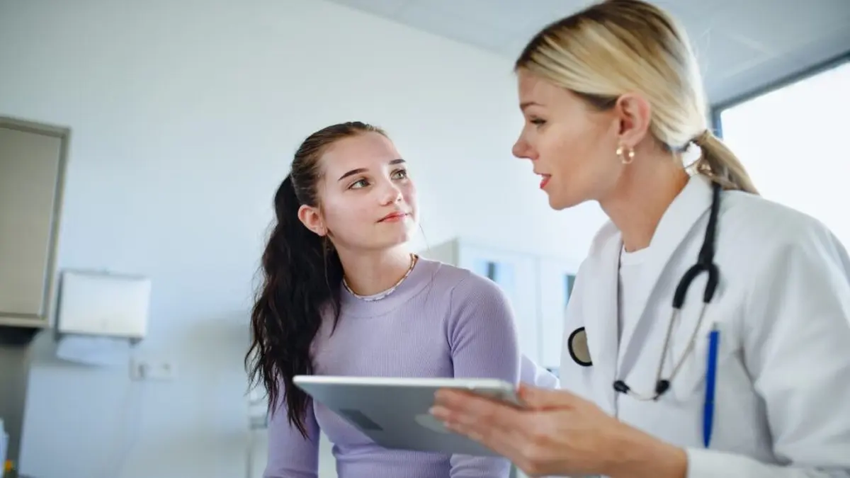 Eine Ärztin bespricht mit einer Patientin gesundheitliche Themen und zeigt Informationen auf einem Tablet.