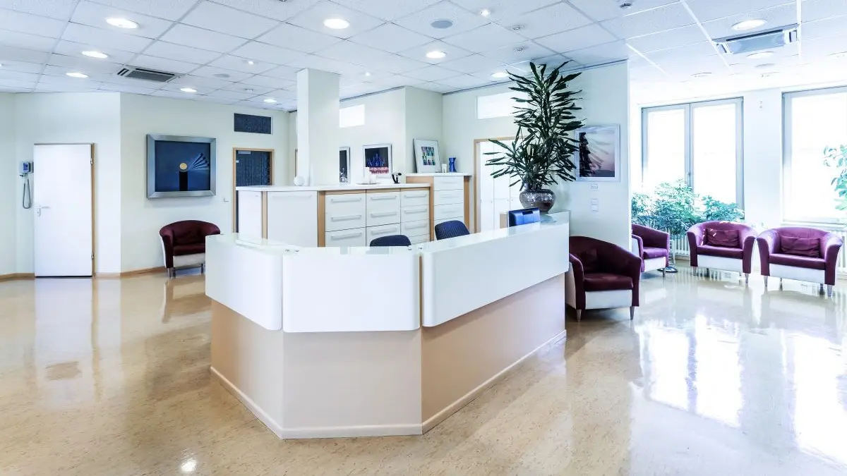 Moderner Empfangsbereich einer Arztpraxis mit hellen Möbeln, Pflanzen und komfortablen Sitzgelegenheiten.
