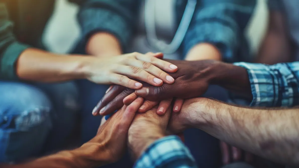 Symbolische Darstellung von Gemeinschaft und Unterstützung durch ineinandergelegte Hände, die Solidarität und Zusammenarbeit repräsentieren.