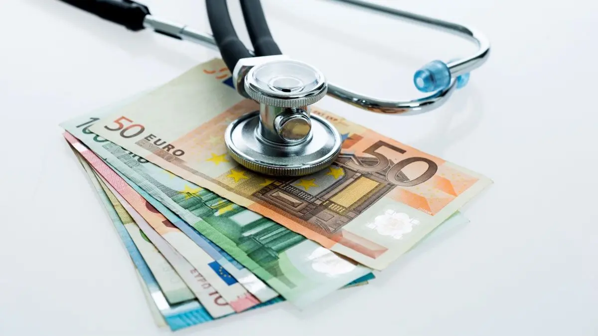 Ein Stethoskop liegt auf einem Stapel Euro-Geldscheine und symbolisiert die Verbindung von Medizin und Finanzen.