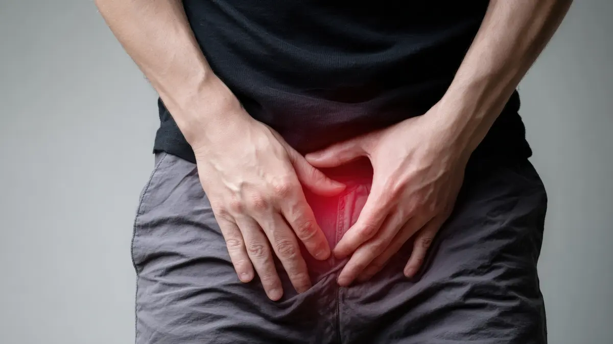 Mann hält sich die Leiste aufgrund von Schmerzen, Symbol für Männergesundheit