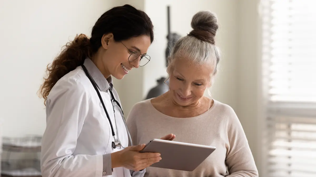 Ärztin erklärt einer Patientin mithilfe eines Tablets die Therapieoptionen bei Melanom.