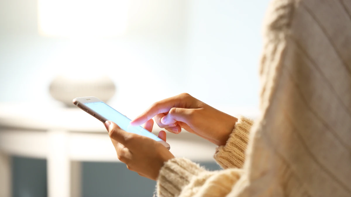 Smartphone im Fokus, man sieht die Hände einer Frau, die das Smartphone bedient.