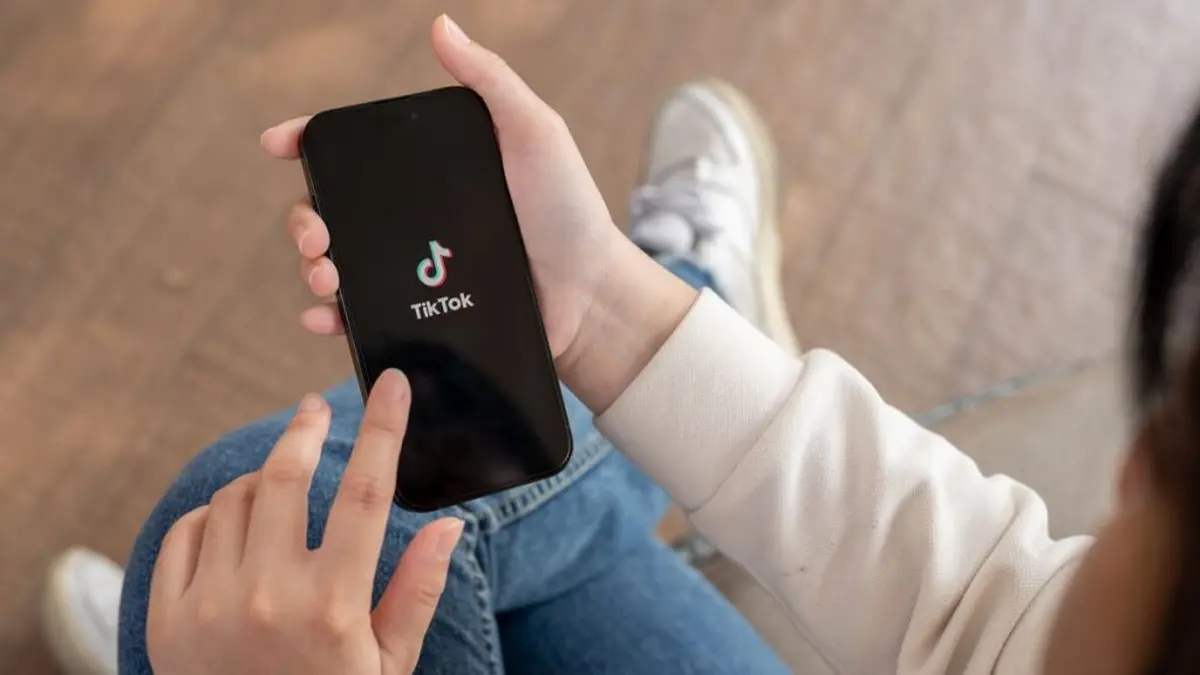 Person hält Smartphone mit geöffneter TikTok-App in der Hand