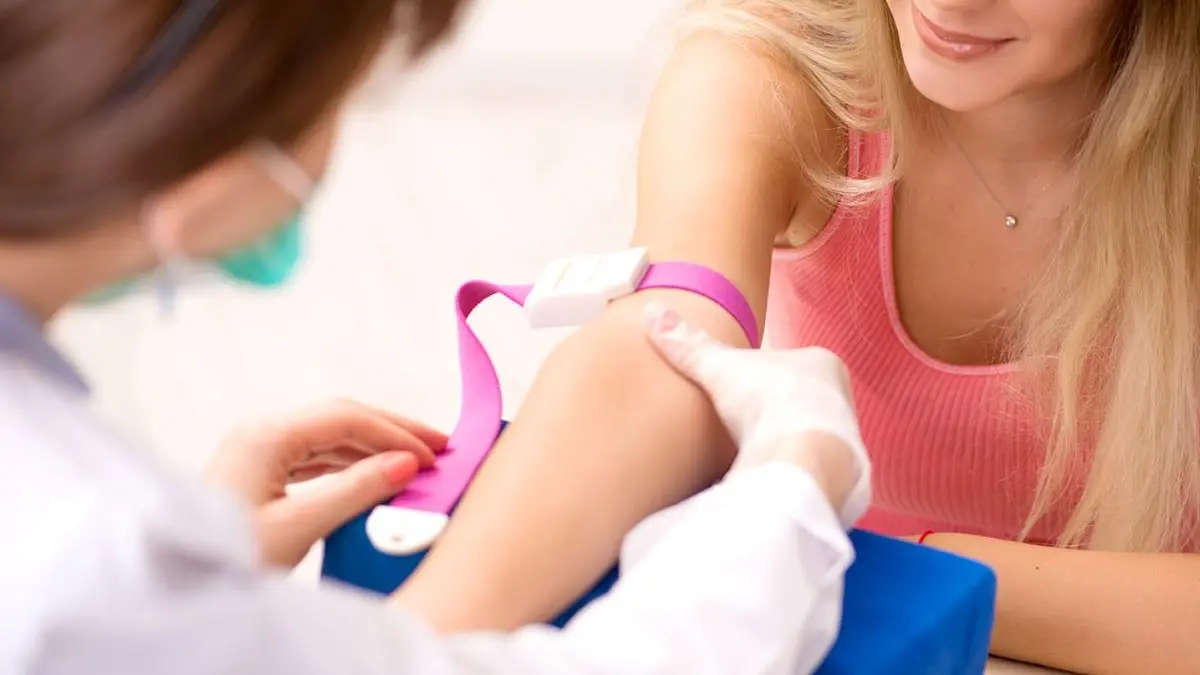 Eine medizinische Fachkraft bereitet einen Bluttest vor, indem sie einem Patienten eine Manschette am Arm anlegt.