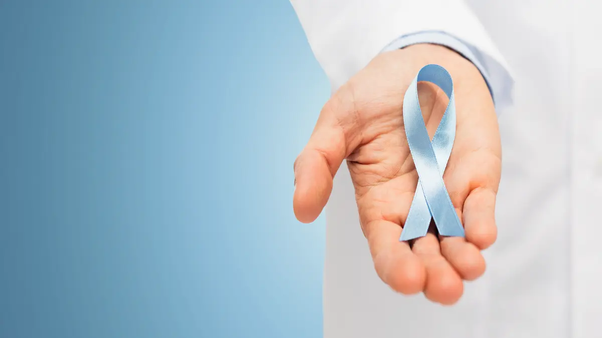 Hand hält eine blaue Schleife, Symbol für das Bewusstsein und die Unterstützung bei Prostatakrebs