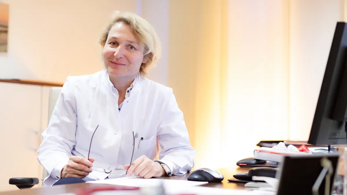 Ärztliche Fachperson im weißen Kittel am Schreibtisch in einem Büro, im Kontext einer Studie zur Immuntherapie bei Darmkrebs