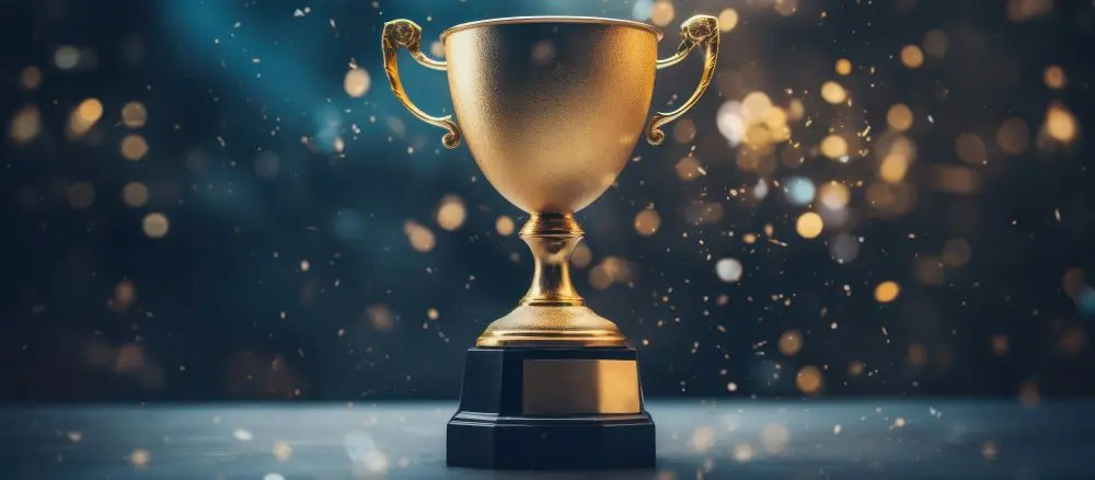 Goldener Pokal vor festlichem Hintergrund – Symbol fuer den UNNA-DERM Preis für innovative Dermatologie