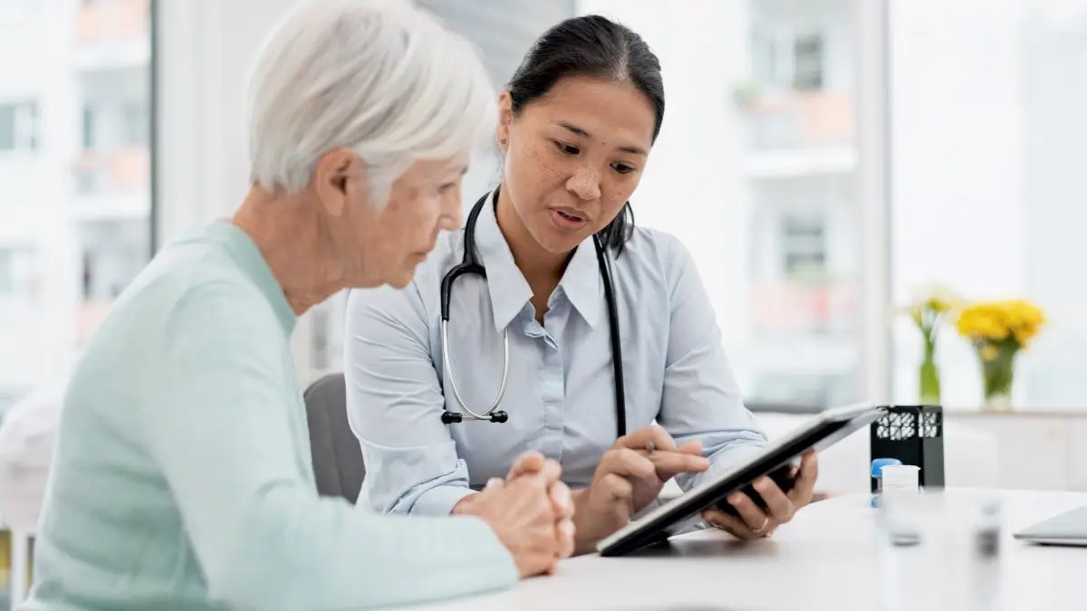 Aerztliche Fachkraft erklaert einer aelteren Person Behandlungsschritte waehrend eines Beratungsgespraechs