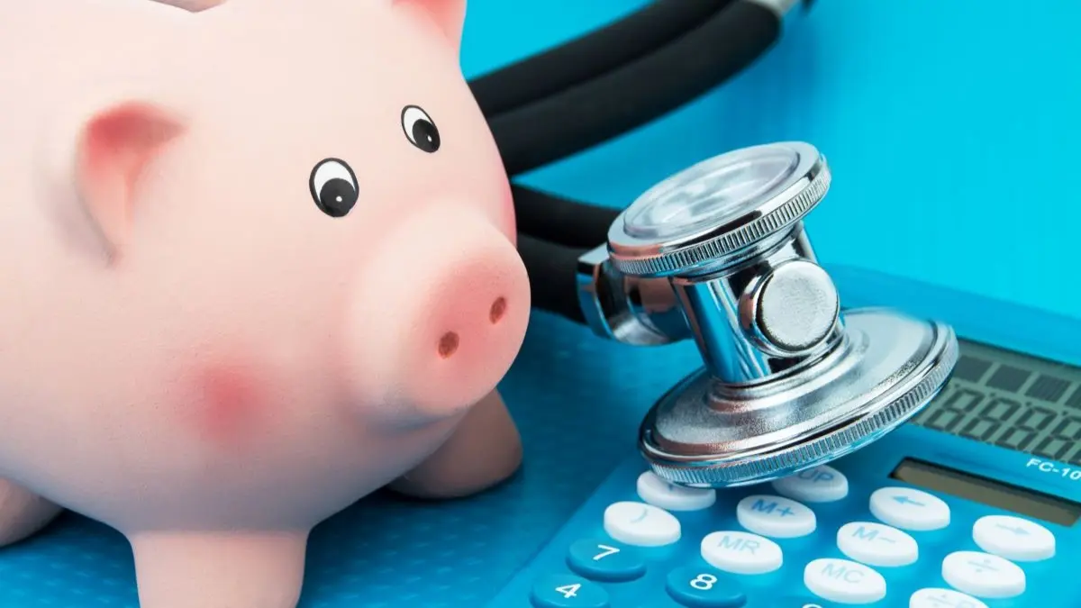 Sparschwein neben Stethoskop und Taschenrechner als Symbol fuer Kritik der grundversorgenden Fachaerzte an den GKV Sparplaenen