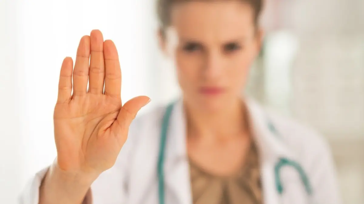 Medizinische Fachperson mit Stethoskop hebt die Hand als Stoppgeste, Symbolbild fuer Forderung den Reformprozess auf Hold zu stellen