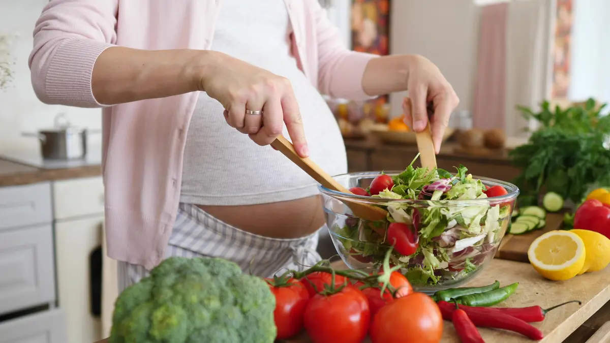 Schwangerefrau die sich einen Salat zubereitet