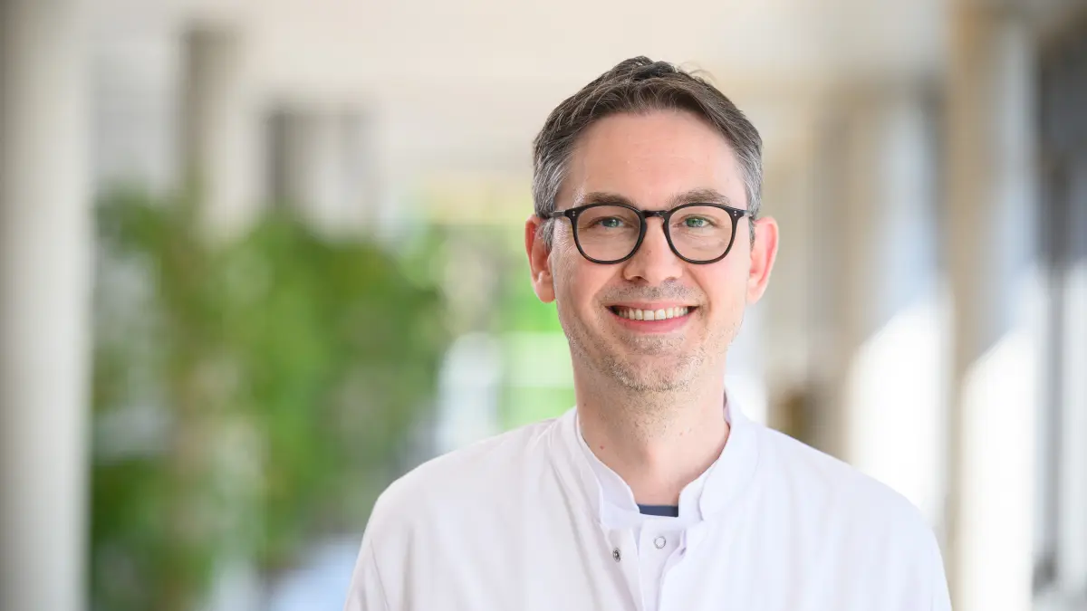 Portraet einer Person im weissen Arztkittel in einem Klinikflur