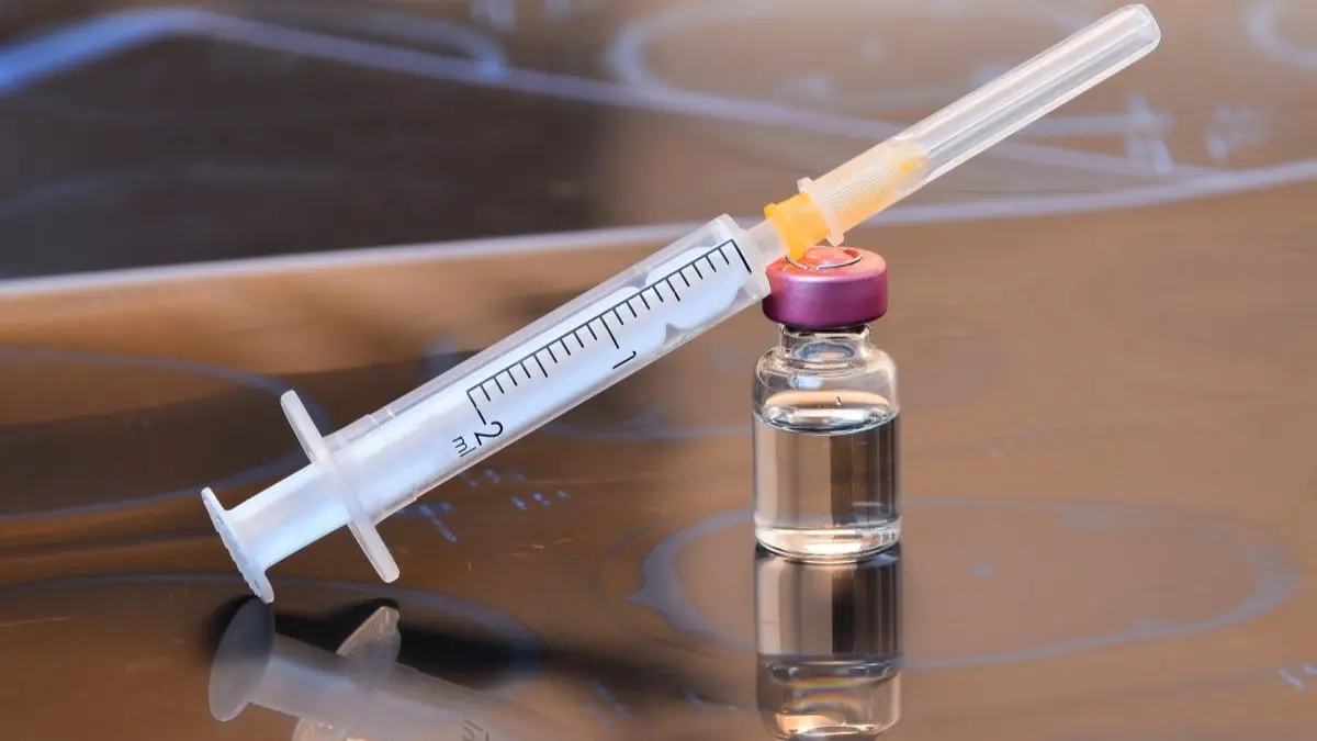 Spritze liegt auf einem kleinen Medikamentenfläschchen, Symbolbild fuer Injektionsbehandlung mit Botulinumtoxin bei fokaler Hyperhidrose