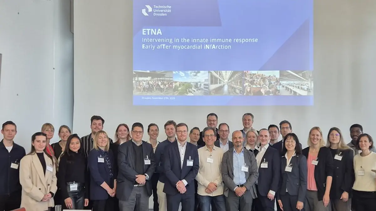 Gruppenfoto der Forschungsgruppe FOR 5953 der TU Dresden vor einer Präsentationsfolie zum Projekt ETNA – Immunsteuerung nach Herzinfarkt