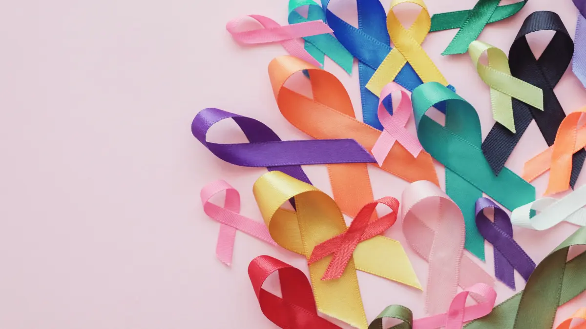 Bunte Bewusstseinsschleifen fuer unterschiedliche Krebsarten auf rosa Hintergrund