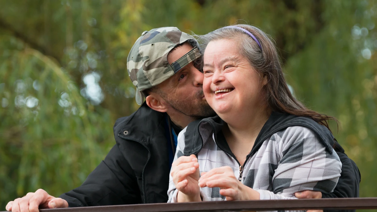 Eine Frau mit Trisomie 21 und ein Mann lachen gemeinsam im Freien – Down-Syndrom und Alzheimer-Risiko