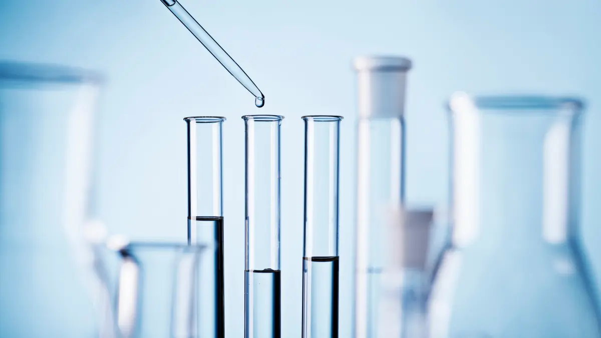 Pipette tropft Flüssigkeit in Reagenzgläser im Labor