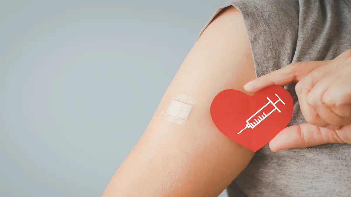 Person hält rotes Herz mit Spritzenicon an den Arm mit Pflaster nach einer Impfung – Symbolbild für RSV-Impfung als Herzschutz bei kardiovaskulären Erkrankungen