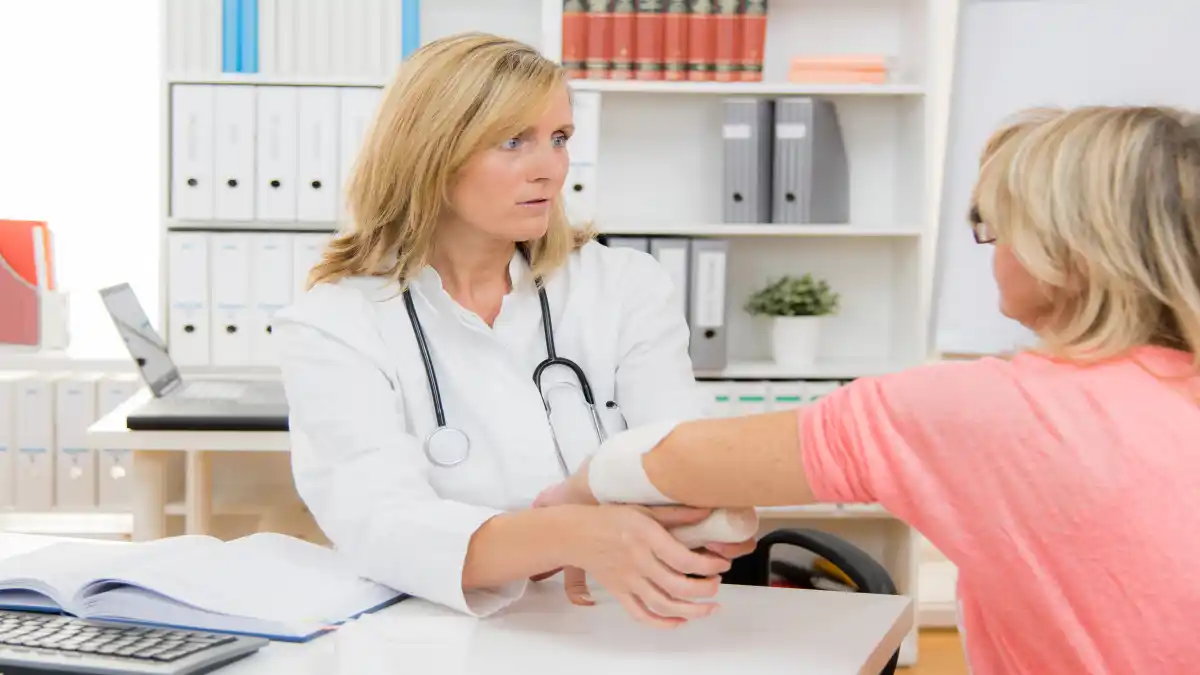 Auf dem Foto verbindet eine Ärztin den Arm einer Patientin.