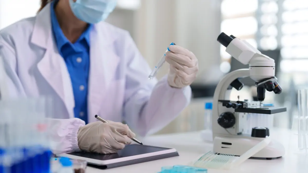 Wissenschaftlerin im Labor mit Pipette, Mikroskop und Tablet bei der Forschungsarbeit